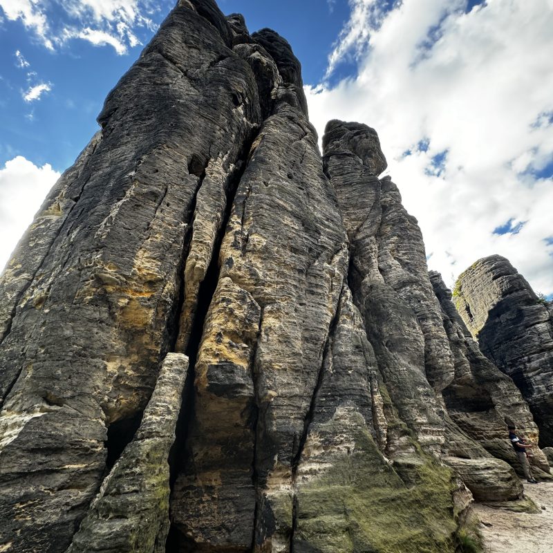 Tall rock formations under a blue sky with clouds.