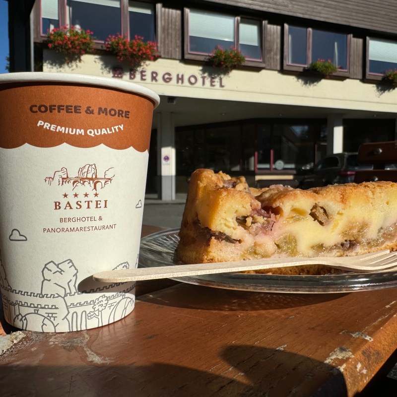 Coffee cup and slice of fruit cake on a table outside a hotel.
