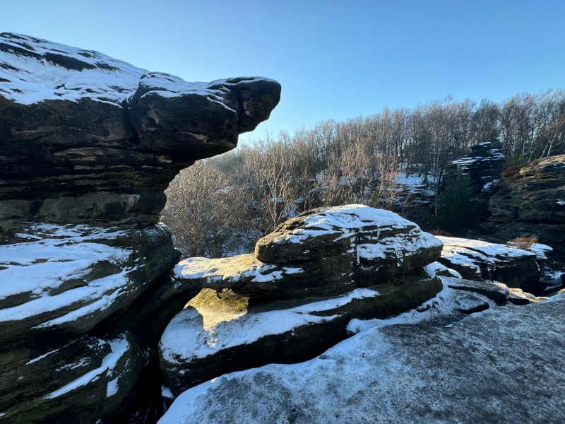 Snowy rock formations with trees in the background under a clear blue sky.