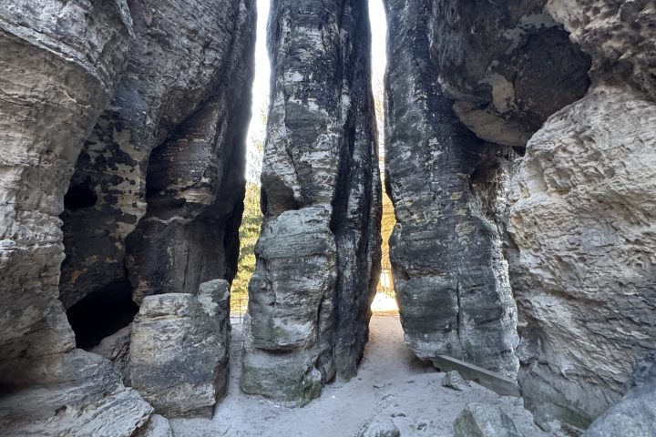 Narrow canyon passage between tall rock formations with a sandy floor.