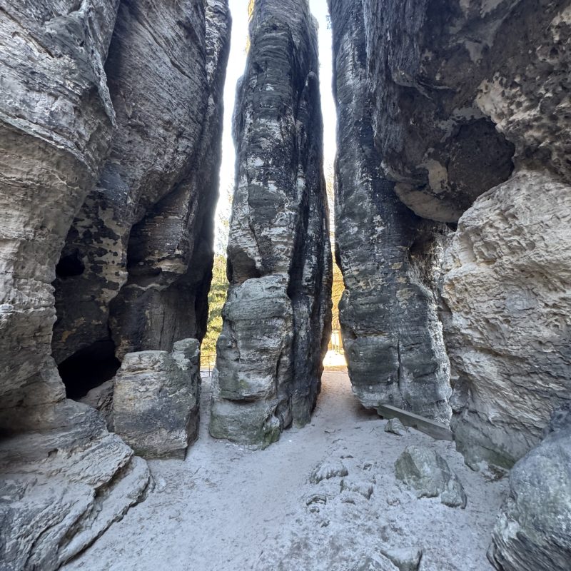 Narrow canyon passage between tall rock formations with a sandy floor.