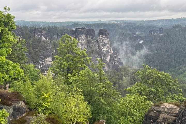 Rock formations and dense green forest under cloudy sky