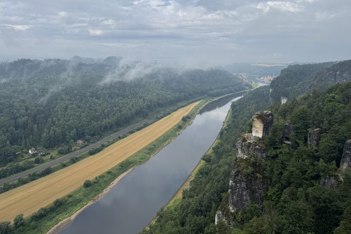 River winding through forested landscape under a cloudy sky.