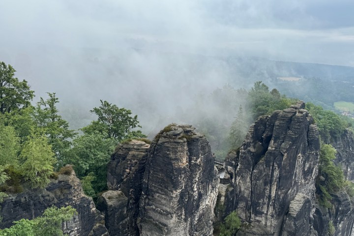Foggy landscape with rocky cliffs and trees on a cloudy day.