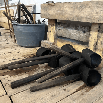 Cluster of wooden tools and wooden pallets on a wooden floor.
