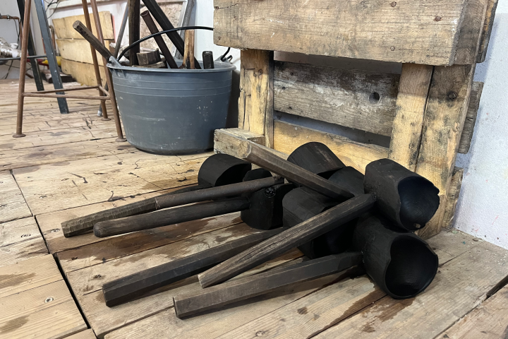 Cluster of wooden tools and wooden pallets on a wooden floor.