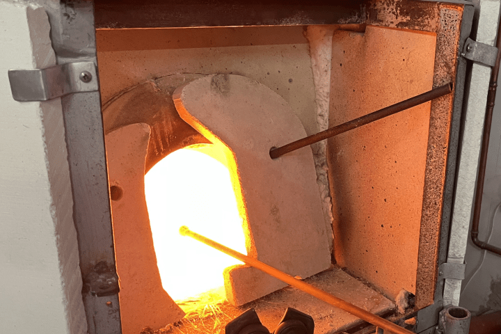 Open furnace with bright orange glow heating a metal rod.
