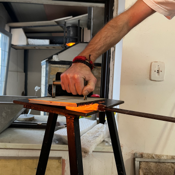 Person engraving metal plate using hand press in a workshop.