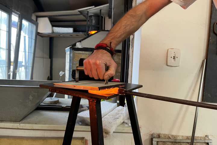 Person engraving metal plate using hand press in a workshop.