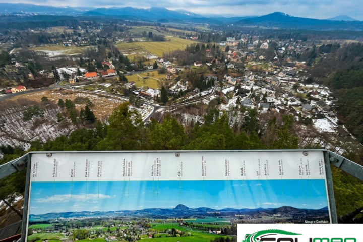 Panoramic view of a snowy village landscape with a tourist map in the foreground.