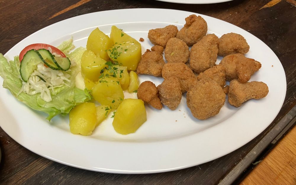 Plate with salad, potatoes, and breaded nuggets.