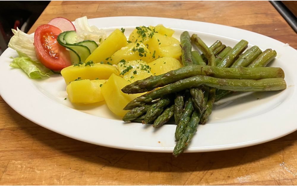 Plate of asparagus, potatoes, cucumber, tomato, and lettuce.