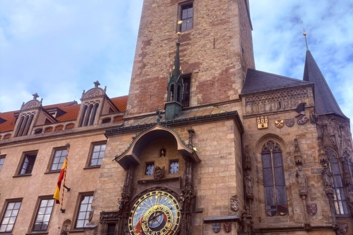 Historic clock tower with ornate astronomical clock on a cloudy day.