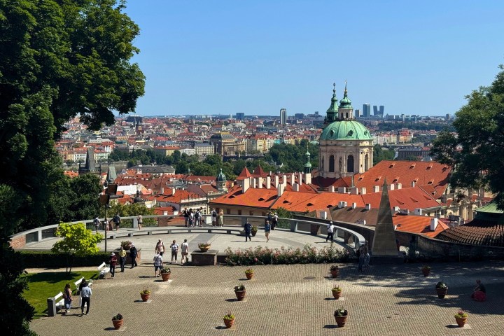 Cityscape view with red rooftops, green dome, and distant skyline under blue sky.