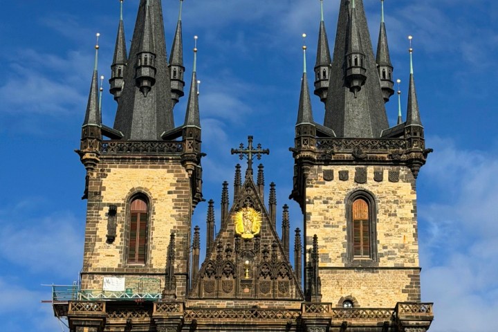 Gothic church with twin spires against blue sky.