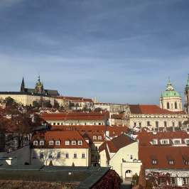 Panoramic view of Prague with red-roofed buildings and St. Vitus Cathedral.