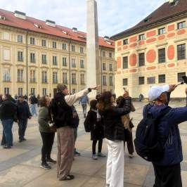 Tourists taking photos in an old European square with historic buildings.